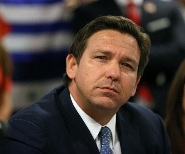 ron desantis sits at table