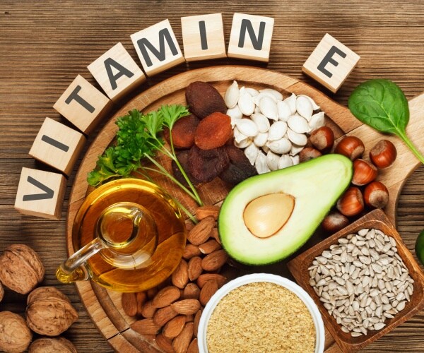 foods rich in vitamin E on wooden board, with wooden blocks spelling out Vitamin E