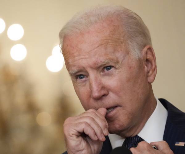 biden puts his thumb to his mouth during a press conference