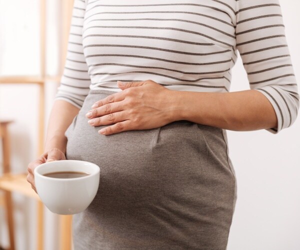 pregnant woman holding cup of coffee