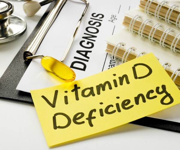 "vitamin D deficiency" on yellow sticky note, stethoscope, vitamin D supplements