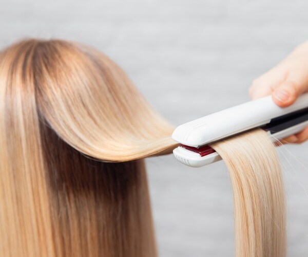 woman with longe blonde hair getting a hair-straightening treatment