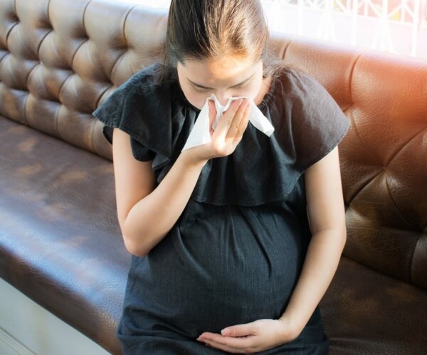 pregnant woman not feeling well sitting on couch