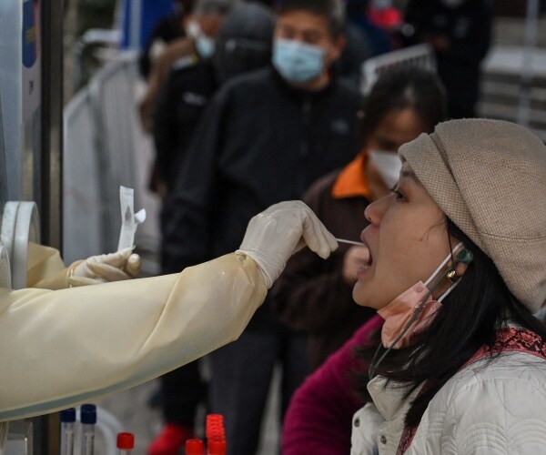 a health worker takes a swab sample from a woman to test for covid-19