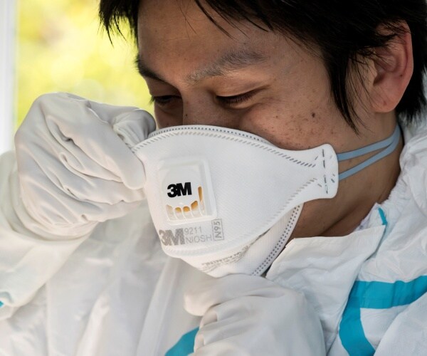 man wears an n95 mask from 3m with a white protective suit on 