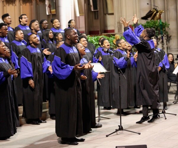 howard university gospel choir dressed in black and blue robes sings on stage