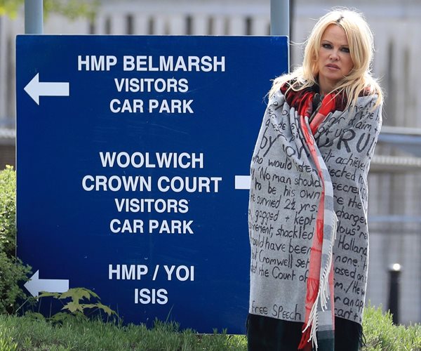 actress pamela anderson stands next to a sign at london's belmarsh prison wrapped in a shawl