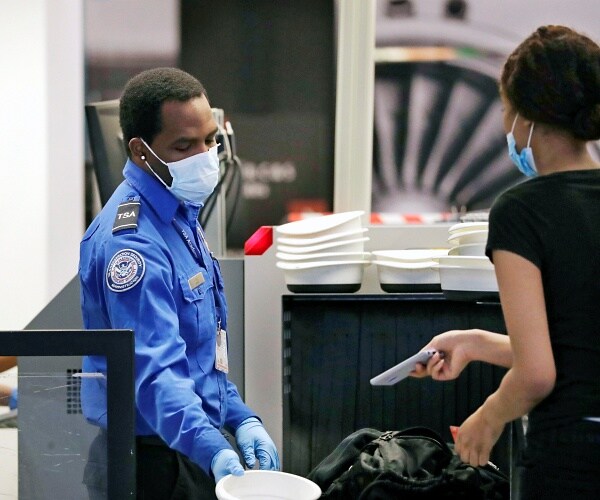 tsa officer wearing mask screens passenger