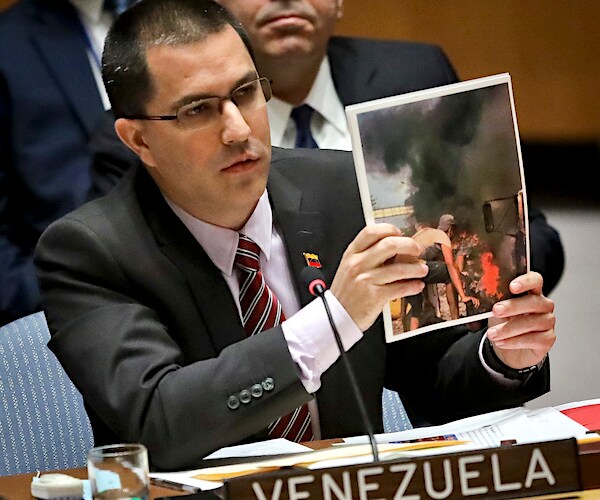 during a united nations security council meeting, jorge arreaza holds up a photo of opposition violence in venezuela