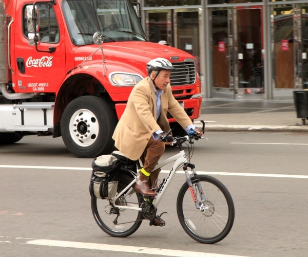 an older man on bicycle on busy street riding to work