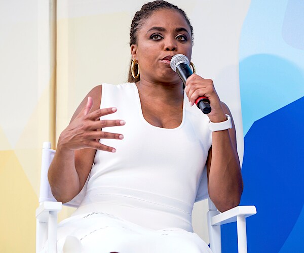 jemele hill sits in a chair on stage and speaks into a mike during a conference