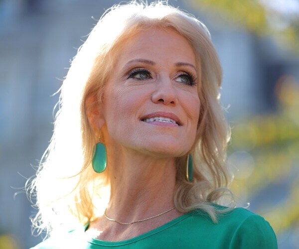 kellyanne conway in a green top and earrings standing outside