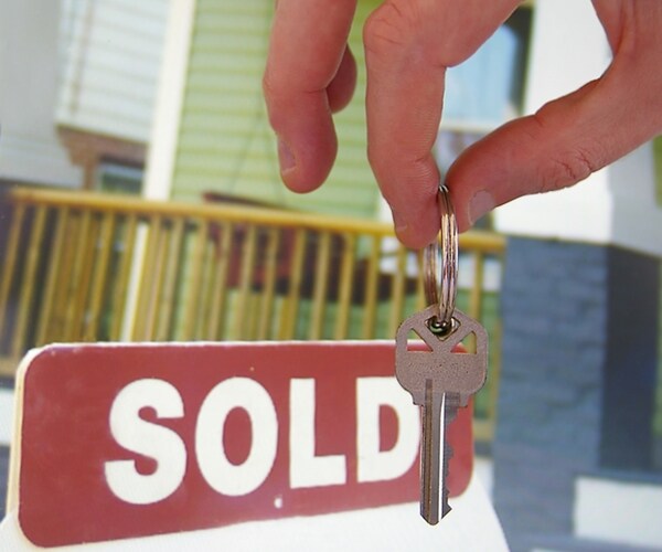 house for sale with sold sign and hand holding a key 