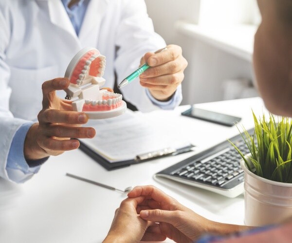 dental practitioner going over model of mouth/teeth with patient