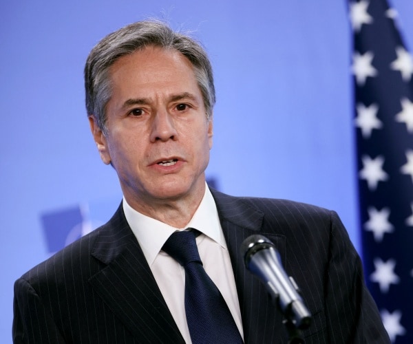 antony blinken speaks in front of a u.s. flag