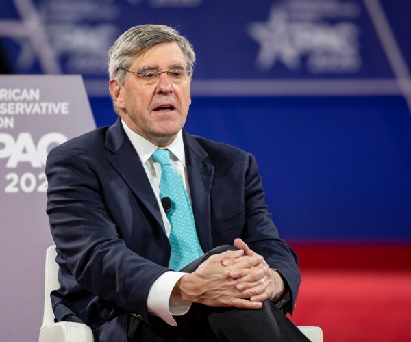 moore in a suit and aqua blue tie speaking at cpac