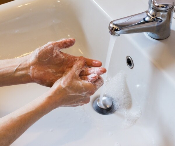 person washing their hands with soap at a sink