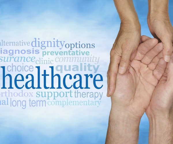 female hands gently cradling male hands on a pale misty blue vignette background with a healthcare word cloud 