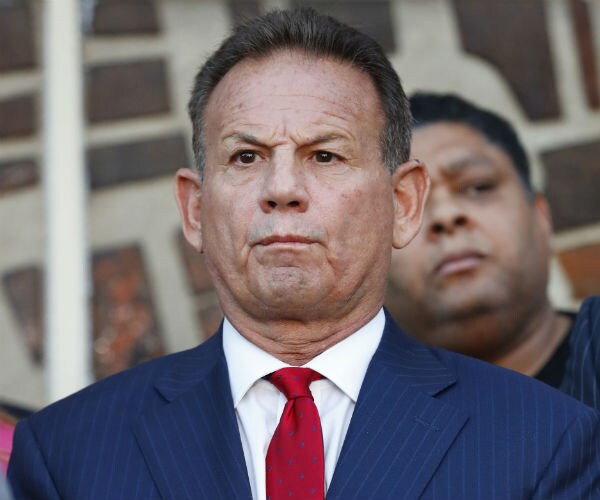 scott israel is showning in blue suit, white dress shirt and red tie