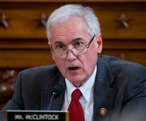 mcclintock in a striped dark gray suit and red tie