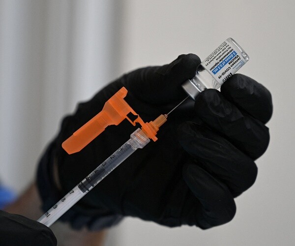 hand holds vial as it fills syringe