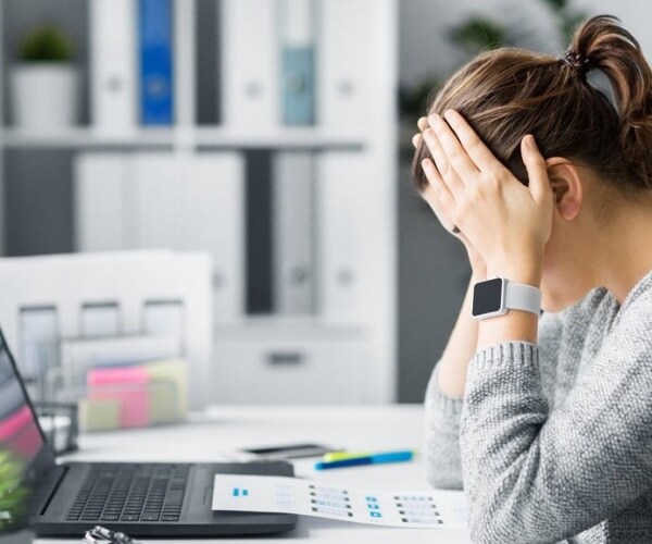 female college student looking stressed out at desk, looking at laptop