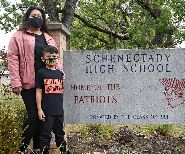 kristina negron and her son stand in front of sign