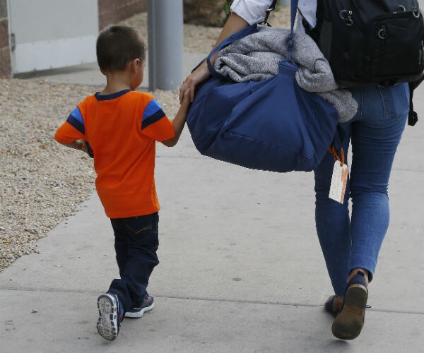 a three-year old child from honduras being helped by a representative of southern poverty law center.