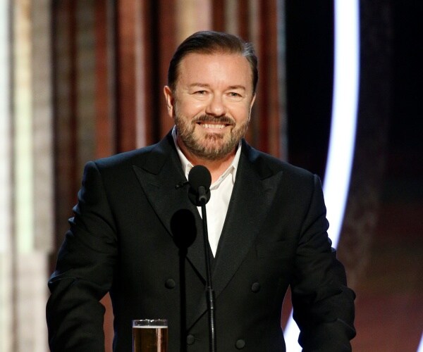 gervais in a black suit and white shirt speaking at the golden globes