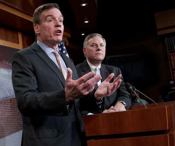 mark warner addresses the media with richard burr looking on