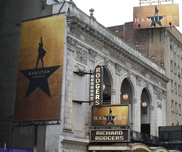 outside of rodgers theatre with three signs displaying the hamilton logo