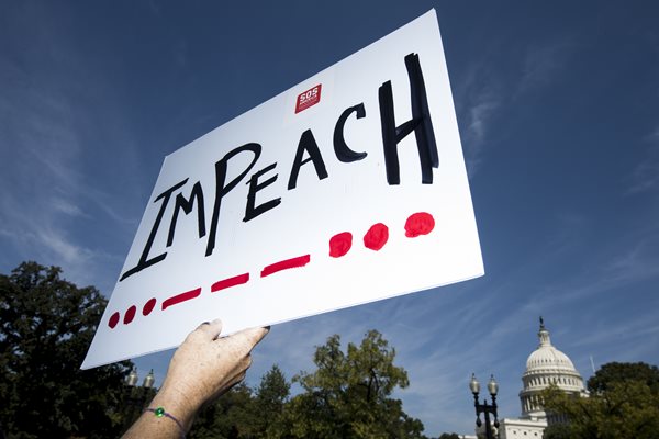 a woman holds up a sign to impeach