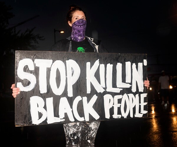 demonstrator holds up a sign to stop killing black people