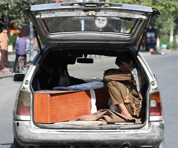 people sitting the the back of a hatchback car with a coffin