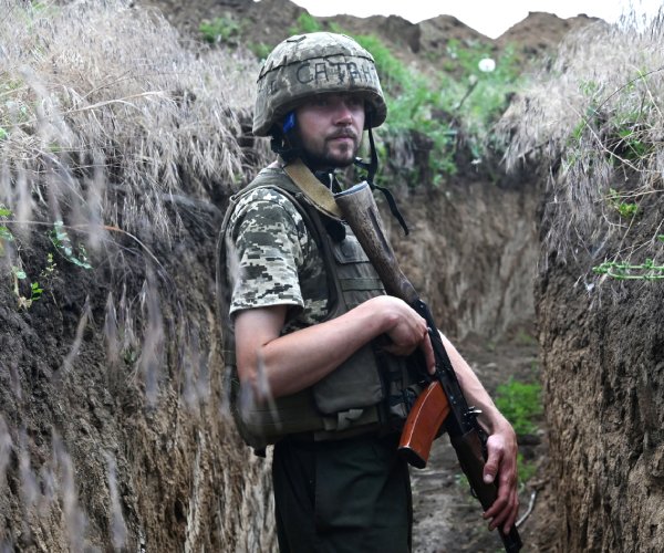 a ukrainian serviceman stands guard in a trench between the southern cities of mykolaiv and kherson