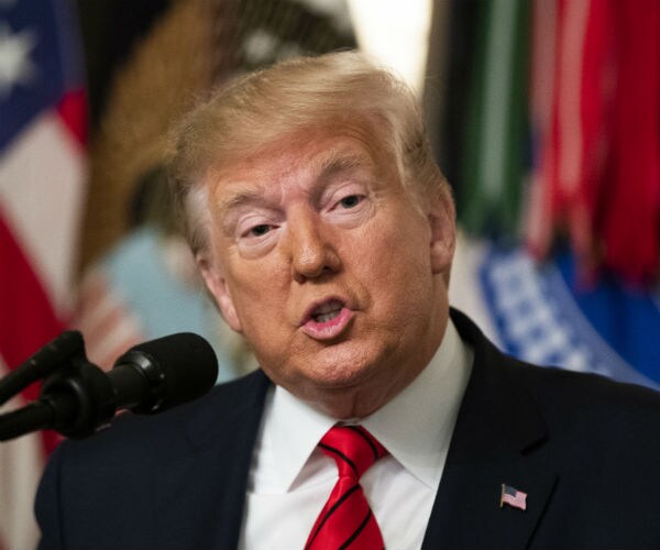 president donald trump is shown in dark suit, white dress shirt and red stripped tie 