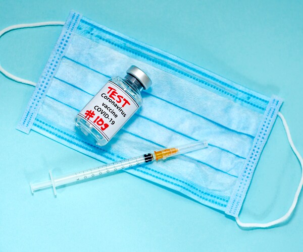 a face mask and a syringe laying on a table with a medicine capsule