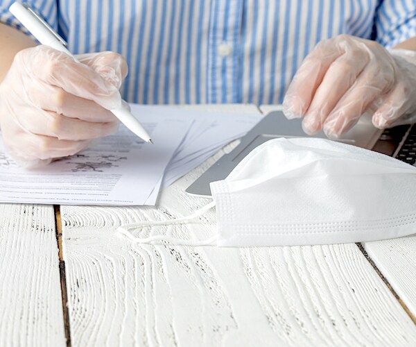 a man fills out paperwork with his face mask laying on a white table