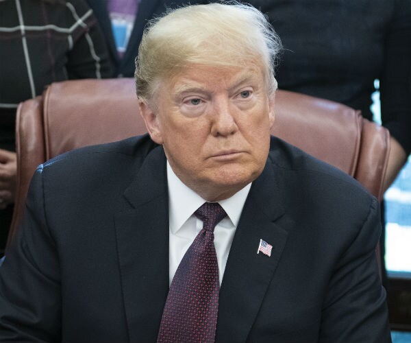 president donald trump sits and listens to a question in the oval office at the resolute desk