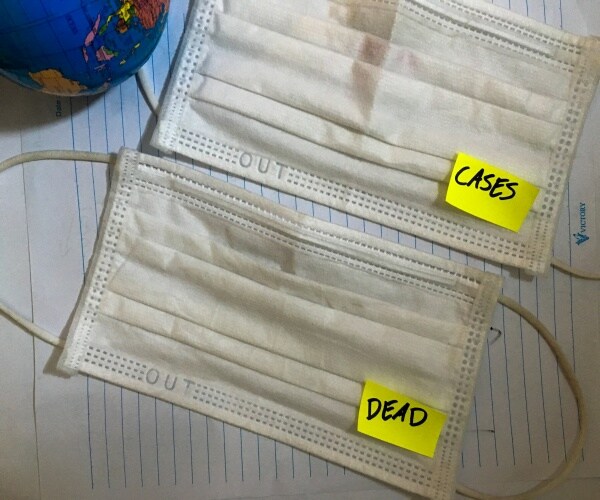 two surgical masks, one with a post-it note saying cases, the other with post-it saying deaths