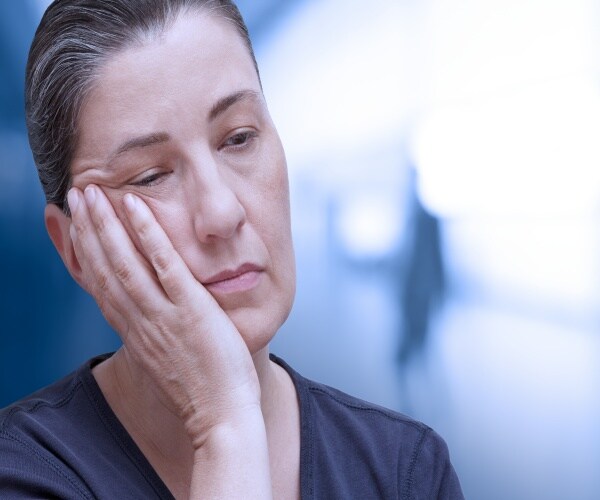 fatigued woman with hand on her cheek