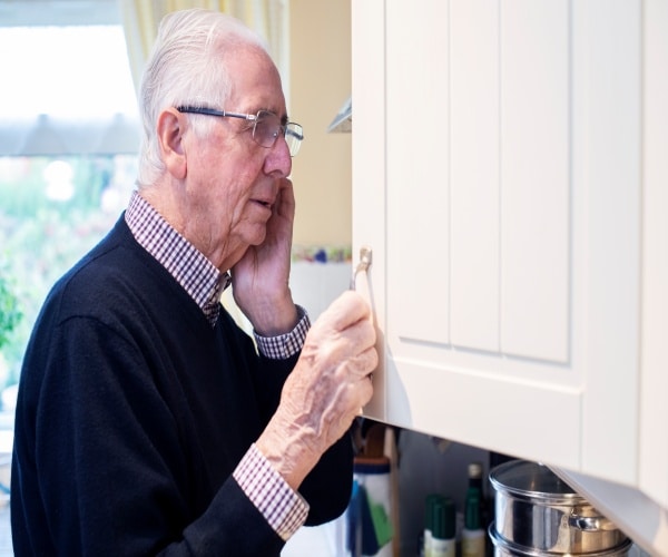 a man looking in cabinet looking confused