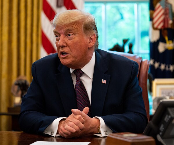 donald trump sits behind his desk in the oval office