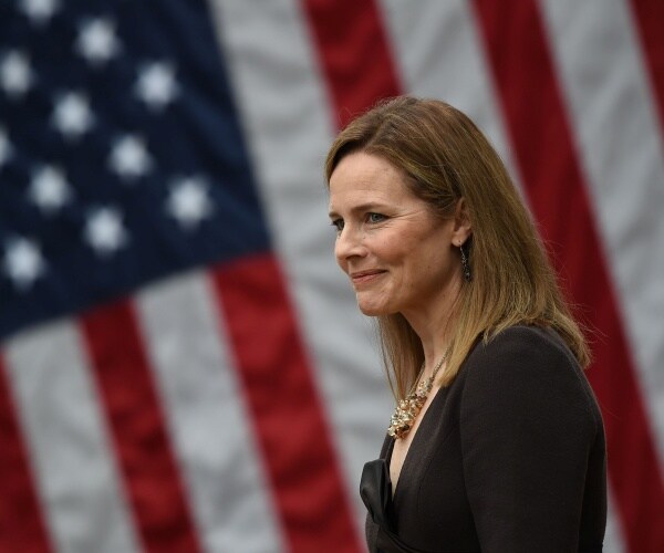 barrett in a black dress standing in front of the us flag