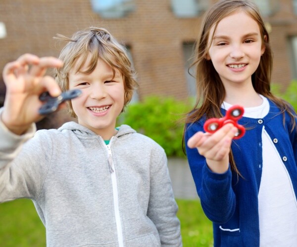 two schoolchildren playing with fidget spinners