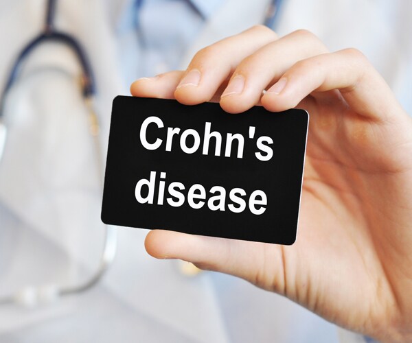 a hand holding a card that reads crohns disease