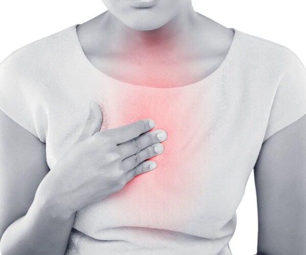 woman with hand on chest suffering from reflux pain