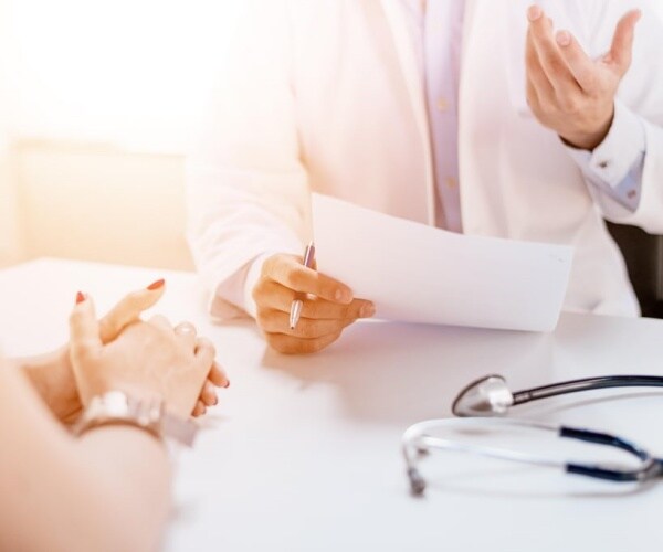 doctor holding a consent form in hands while describing the details to a patient