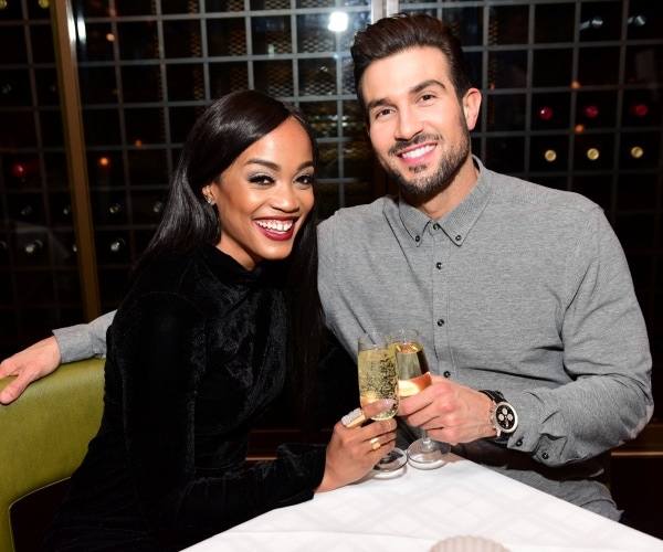 rachel lindsay in a black dress sitting at a restaurant with bryan abasolo in a gray shirt