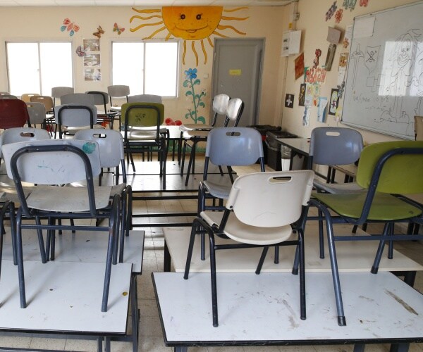 chairs are put up on desks in an elementary school classroom